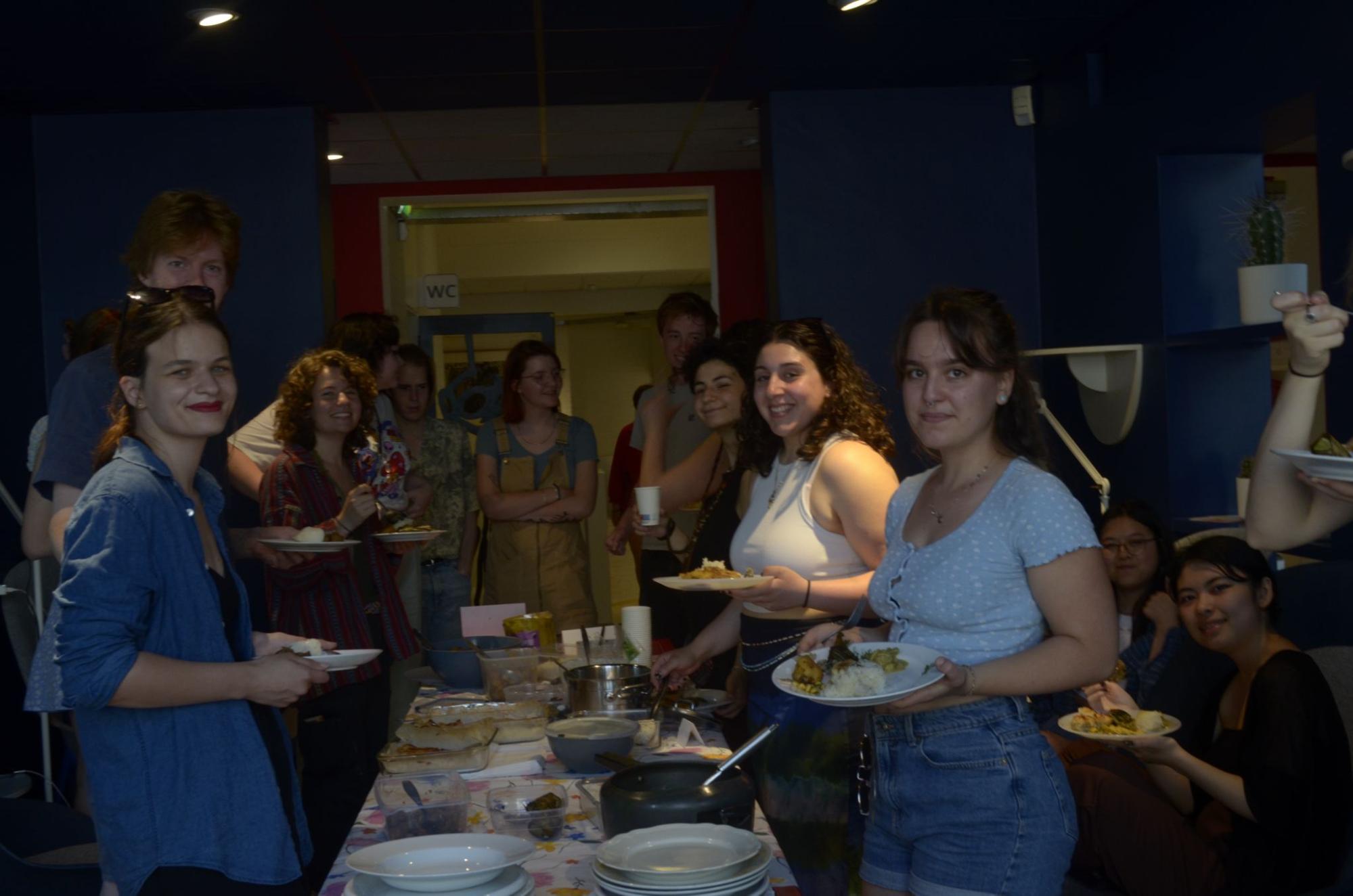 Potluck and Cookbook - students gathering around food at the potluck event